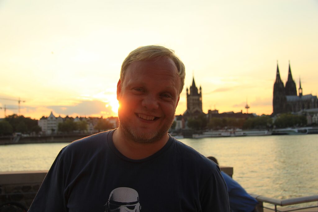Guide & Inhaber entdeckungstouren.koeln Stefan Conée vor Kölner Altstadtpanorama mit Groß Sankt Martin, Fernsehturm und Kölner Dom